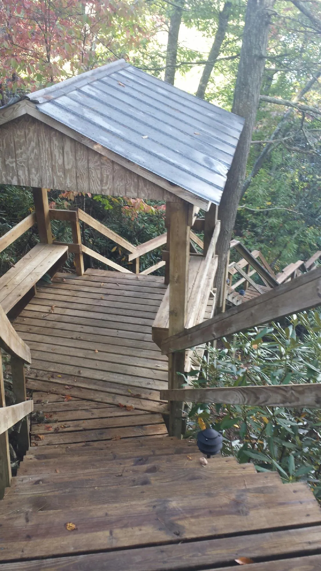 Metal roofed shelter over wooden steps on a wooded walkway — Skylight Repair & Installation work by our crew in Grand Island